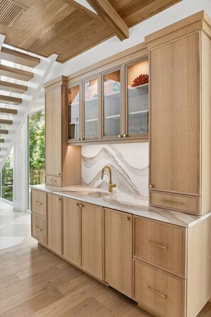 A kitchen with wooden cabinets, a marble backsplash, and a modern faucet. - Stunning newly built luxury retreat in the heart of Isle of Palms (Isle of Palms)