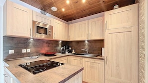 Une cuisine moderne avec des meubles en bois, un four à micro-ondes encastré, une cuisinière et un évier.