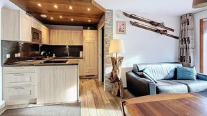 Une cuisine moderne avec des meubles en bois, un îlot central et un coin repas doté d’une table en bois.