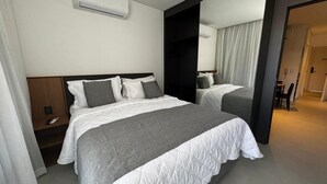 Una habitación de hotel con una cama grande, una mesita de noche, un armario y un espejo.