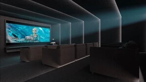 Un cine moderno con una pantalla grande, asientos oscuros y un diseño minimalista.