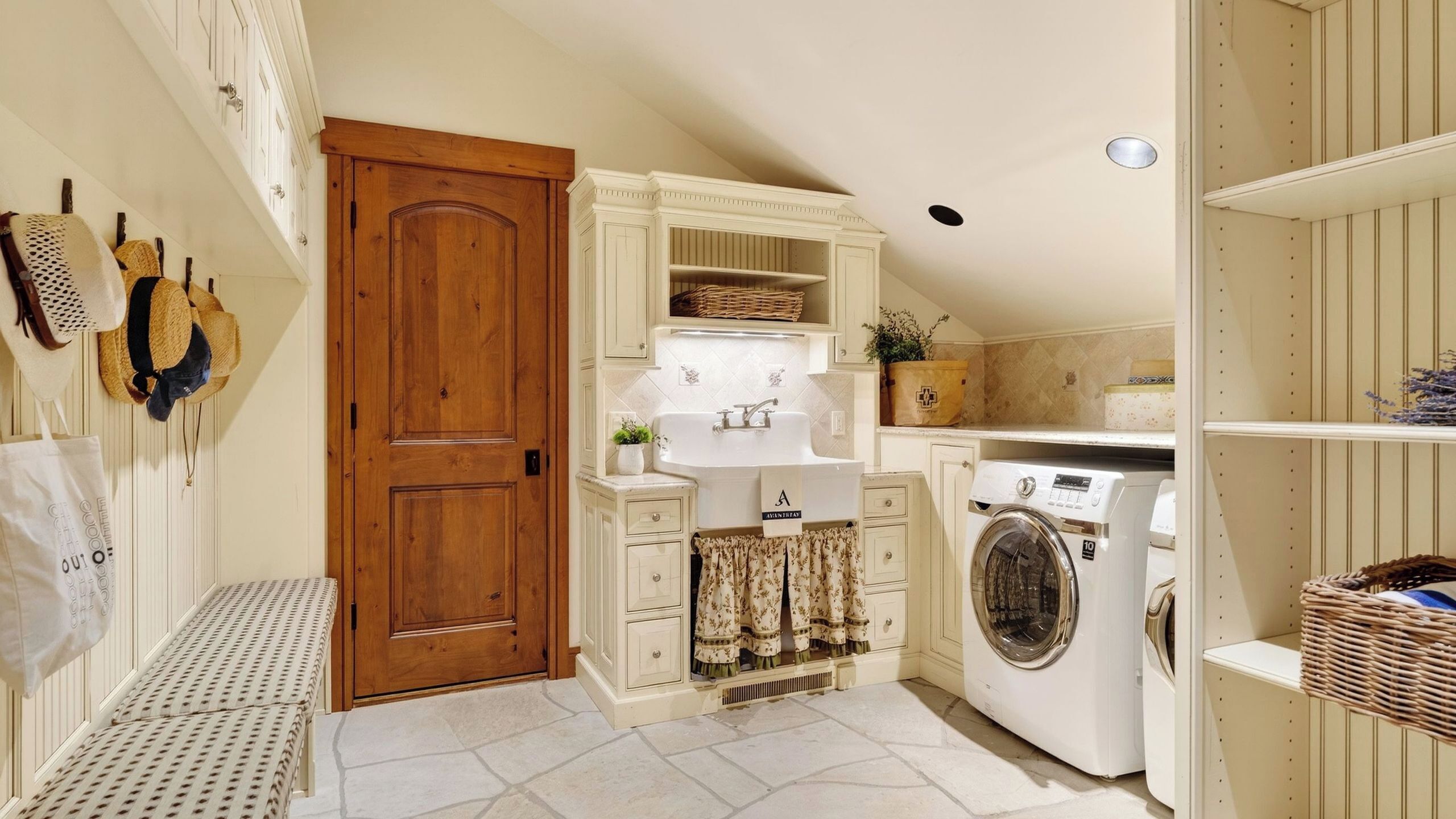 A laundry room with a washing machine, a sink, and a wooden door.