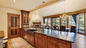 A spacious kitchen with wooden cabinets, a large island, and a dining area with a chandelier.
