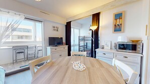 Eine moderne Küche mit Esstisch, Stühlen, Fernseher und Mikrowelle.