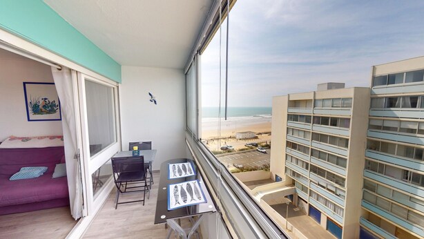 Ein Balkon mit Blick auf den Strand und ein Gebäude.