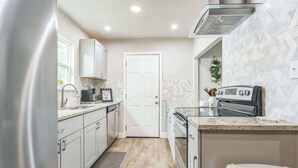 A compact kitchen with white cabinets, a stainless steel range, and a microwave. - Cozy 3BR House in Prime Location (San Antonio)