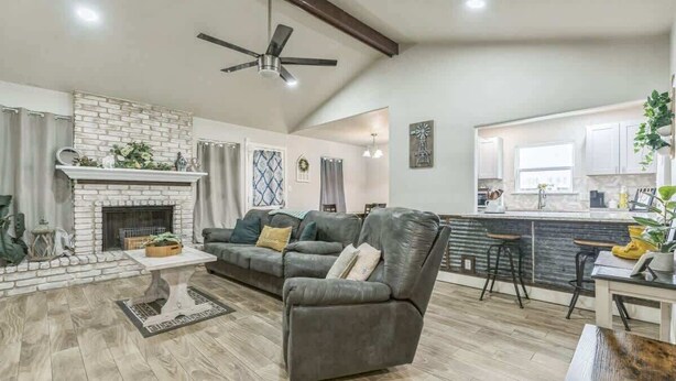 A living room with a fireplace, a sofa, a coffee table, and a dining area with a bar. - Cozy 3BR House in Prime Location (San Antonio)