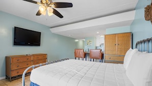 Ein Schlafzimmer mit Bett, Fernseher, Deckenventilator, Kommode und Kleiderschrank.