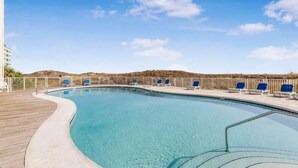 Ein klares Schwimmbecken mit blauen Liegestühlen und einer Holzterrasse.