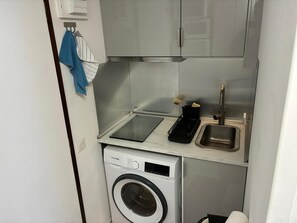Eine kleine Küche mit Waschmaschine, Spüle und einer Arbeitsfläche.