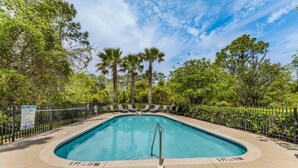 A rectangular pool with a metal handrail, surrounded by a fence and trees. - Driftwood Dunes (Pensacola)