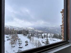 A snowy mountain landscape with a parking area and trees. - 10m from resort center, 7th floor, swimming pool, tv, ski locker, 16m², Le Corbier (Le Corbier)