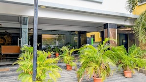 A hotel entrance with potted plants, a staircase, and a modern interior. - Deluxe With Twin Bed Super Townhouse (Hyderabad)