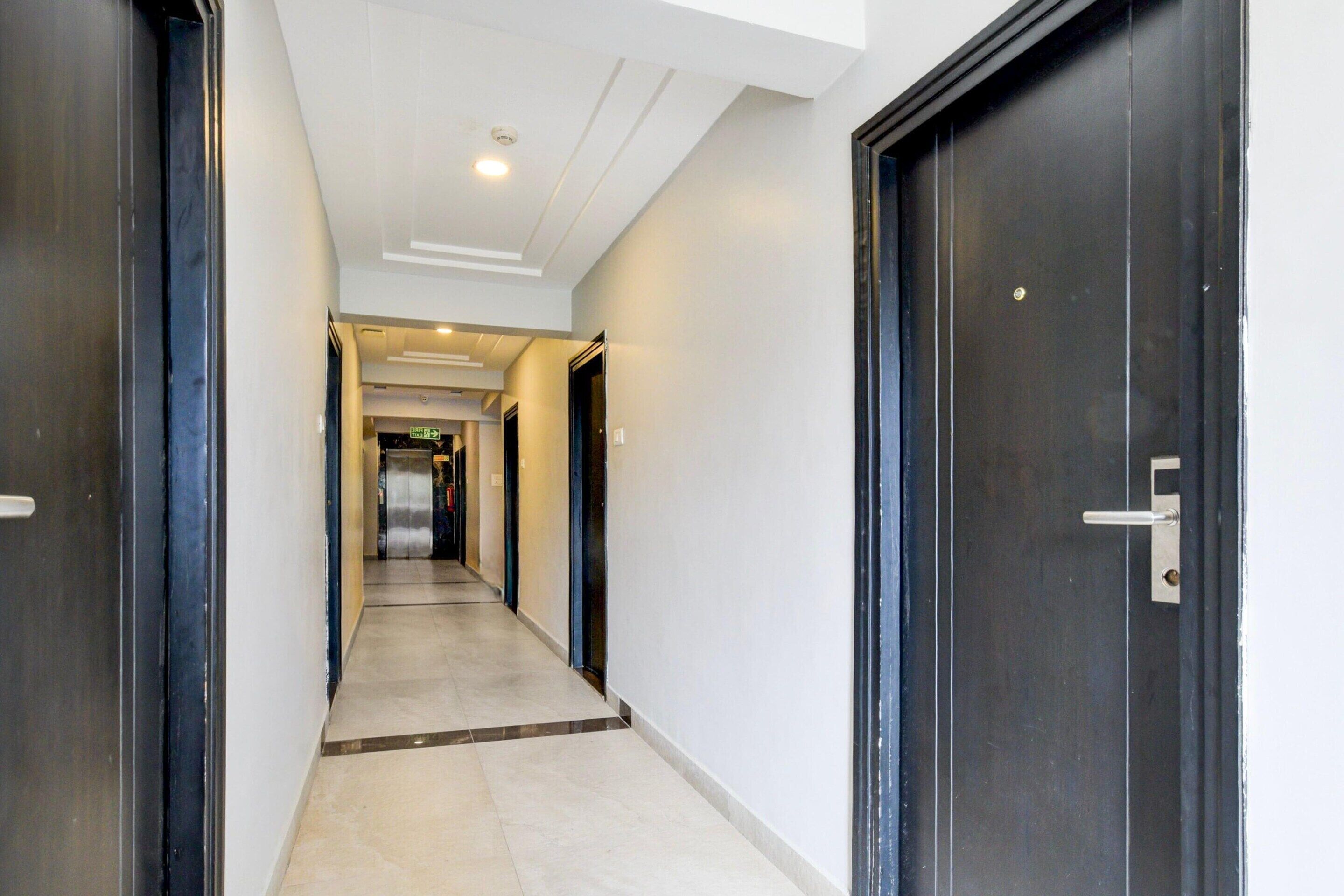 A corridor with doors on both sides, leading to a room with a visible door handle.