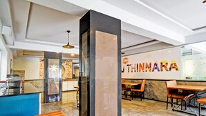 A modern interior with a central pillar, a counter with the name 'THINNARA,' and seating arrangements. - Deluxe With Twin Bed Super Townhouse (Hyderabad)