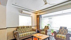 A modern lounge area with sofas, a coffee table, and a ceiling fan. - Deluxe With Twin Bed Super Townhouse (Hyderabad)