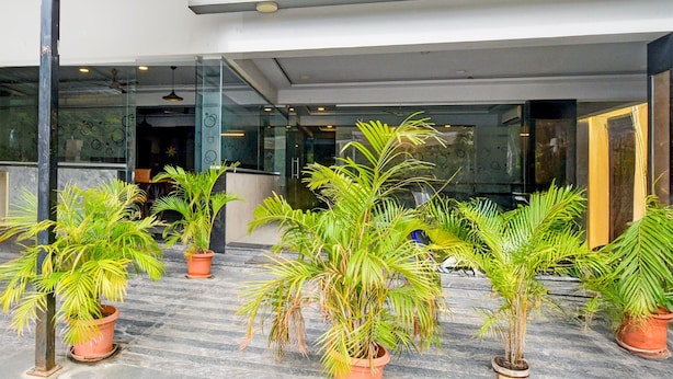 A modern building entrance with potted plants and a reception desk. - Deluxe With Twin Bed Super Townhouse (Hyderabad)
