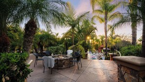 An outdoor patio with a fire pit, lounge chairs, and a stone wall. - Sunset Estate by Avantstay Sleeps 20 Resort-style Pool + Gorgeous Grounds Exclusive Poway Stay (Poway)