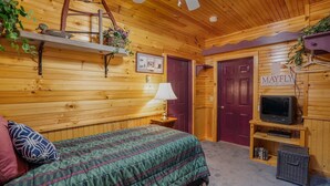 A wooden cabin room with a bed, a lamp, a television, and a door labeled 'MAYFLY'. - Soothing studio apartment - on the Battenkill River in charming, Shushan (Shushan)