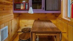 A wooden cabin interior with a dining table, a microwave, and a window. - Soothing studio apartment - on the Battenkill River in charming, Shushan (Shushan)