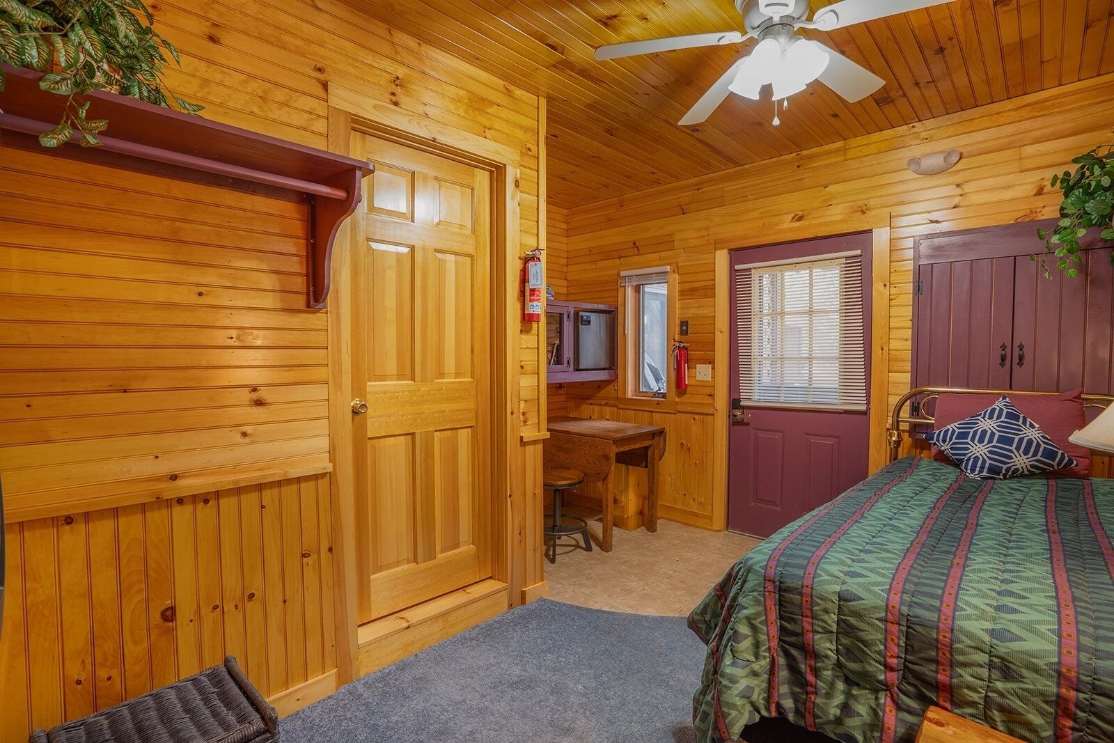 L’intérieur d’une cabine est doté d’une porte en bois, d’un lit recouvert d’une courtepointe à motifs, d’un ventilateur de plafond et d’un petit coin cuisine.