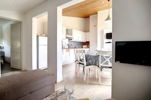 A modern kitchen with white cabinets, a dining area with a table and chairs, and a TV mounted on the wall. - Ski-in/ski-out & foot of the slopes, 3rd floor, view mountain, balcony, tv, ski locker, 66m² (Les Menuires)