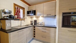 Una cocina compacta equipada con microondas, cafetera y horno integrado.