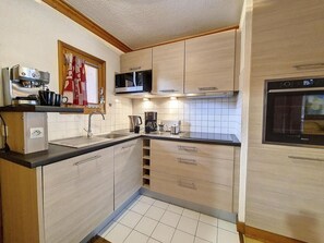 Eine kleine Küche mit Mikrowelle, Kaffeemaschine und Backofen.