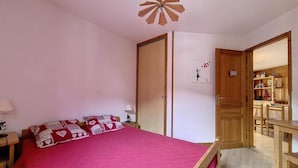 Un dormitorio con una cama, una puerta de madera, un escritorio y una silla.