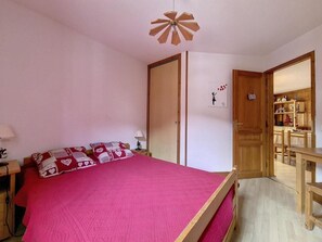 Ein Schlafzimmer mit einem Bett, einer Holztür, einem Schreibtisch und einem Stuhl.
