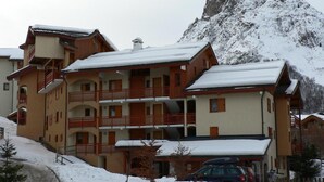 Un hotel de varios pisos con balcones y una montaña nevada al fondo.