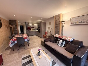 Ein modernes Wohnzimmer mit einer Couch, einem Couchtisch und einem Essbereich mit Tisch und Stühlen.