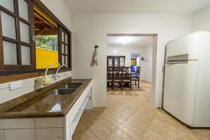 Eine Küche mit einer Granitabdeckung, einem Spülbecken, einem weißen Kühlschrank und einem Essbereich mit Holztischen und einer Tischplatte.