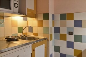 Eine Küche mit Mikrowelle, Spüle und einer Pfanne auf der Arbeitsfläche.