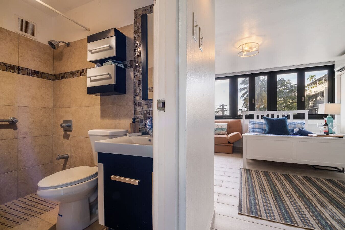 Une salle de bain moderne équipée d’une douche, de toilettes et d’un lavabo, ainsi qu’un espace de vie avec un canapé et une vue sur l’extérieur.