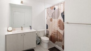 Een badkamer met een witte wastafel, spiegel, toilet en douchegordijn.