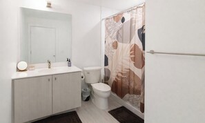 A bathroom with a white sink, mirror, toilet, and shower curtain. - Executive King Condo With Home Cinema | Bowling,Pool,Gym,Sauna,Hot Tub,Lounge (Kitchener)