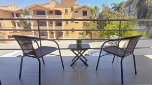 A balcony with two chairs and a small table, overlooking a residential area with buildings and trees. - Nice condo in quiet area 5 minutes from downtown! (Cabo San Lucas)