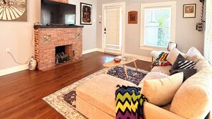 A living room with a fireplace, a sofa, a television, and a ceiling fan.