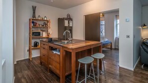 Una cocina compacta con una isla central, microondas, refrigerador y un armario de madera.