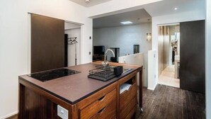 Una cocina moderna con una isla central, electrodomésticos integrados y una despensa amplia.