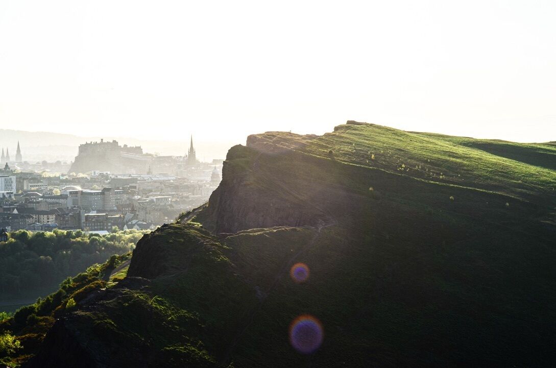 A cityscape with a prominent hill and a distant castle-like structure.