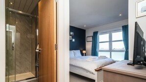 Une chambre d’hôtel équipée d’une douche, d’un lit, d’une table de chevet et d’une fenêtre avec des rideaux.