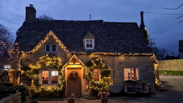 A stone house with a steeply pitched roof, a central door with a wreath, and multiple windows. - 18th Century Cotswolds Cottage | Parking | Garden - Pass the Keys (Bourton-on-the-Water)