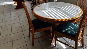 En matplats med ett runt bord, stolar, en takfläkt, en soffa och en tavla på väggen.
