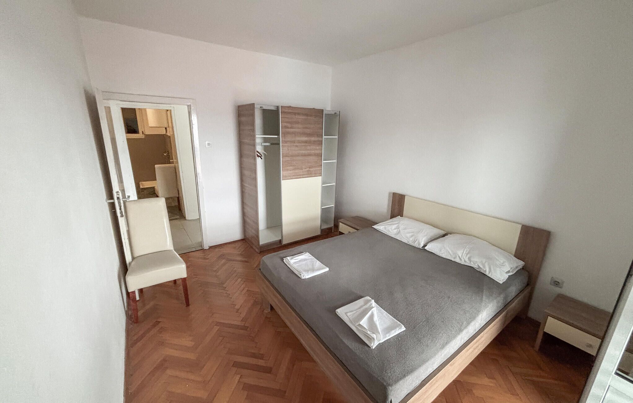 Um quarto com uma cama, uma cadeira, um guarda-roupa e uma mesinha.