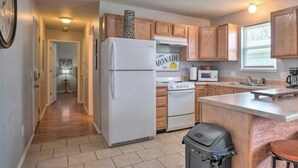 Cocina compacta con armarios de madera, un refrigerador blanco, un microondas y una estufa.