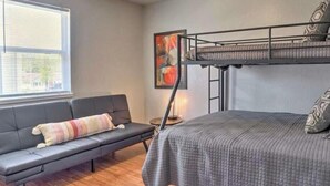 Una habitación compacta con literas, un sofá, una mesita y una ventana.