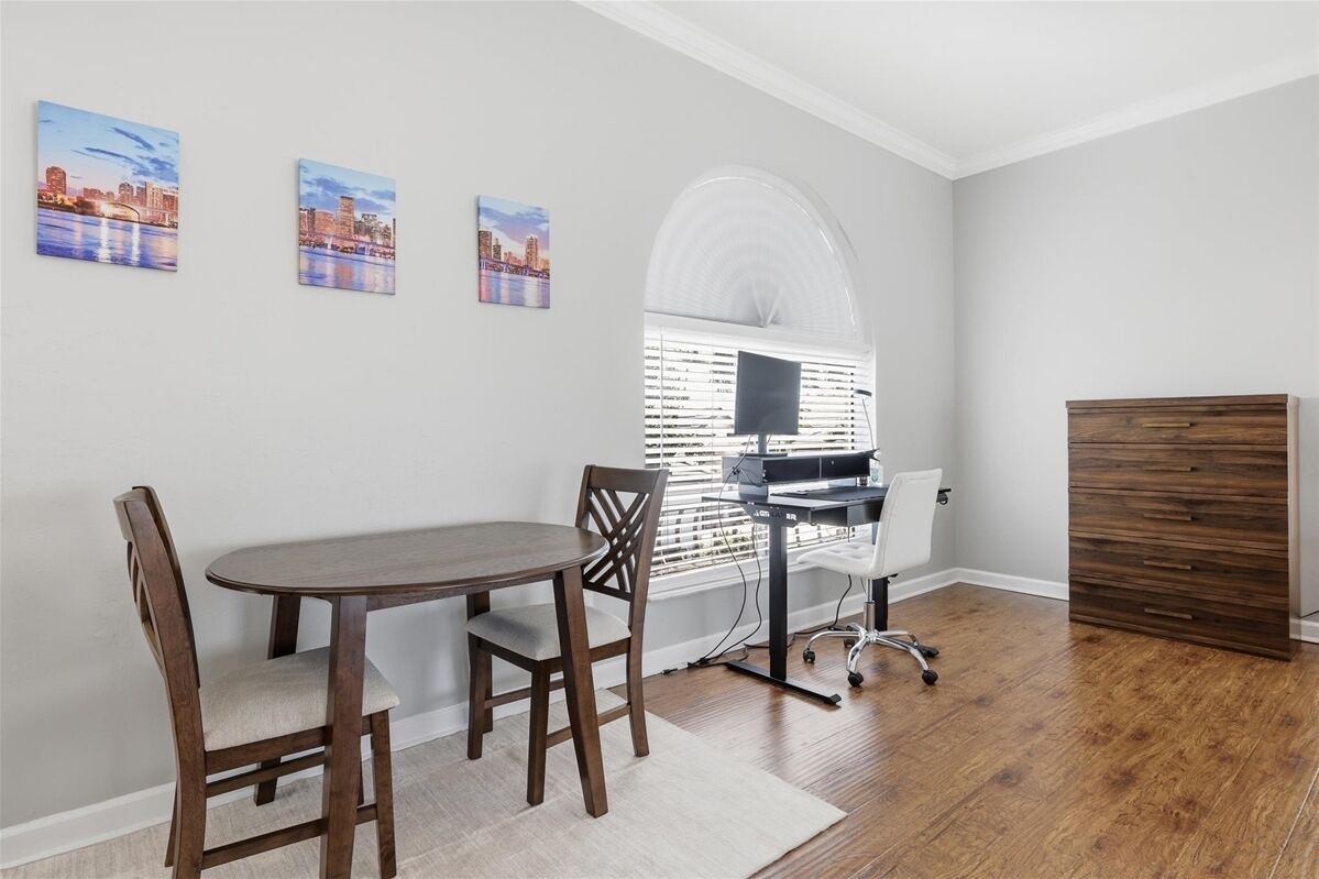 Une pièce comprenant une table à manger, des chaises, un bureau et un meuble de rangement.