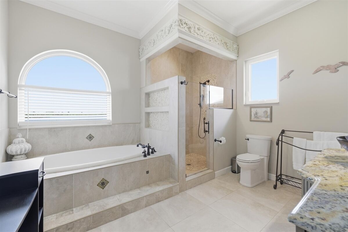 A bathroom with a bathtub, shower, toilet, and a window.